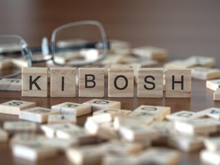 kibosh word or concept represented by wooden letter tiles on a wooden table with glasses and a book