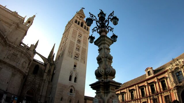 DOLLY SHOT - Farola Fountain and the Catedral de Sevilla (Cathedral of Saint Mary of the See) and La Giralda. Giralda is the name given to the bell tower of the Cathedral.