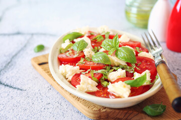 Vegetarian cuisine. Tomato salad with mozzarella and basil, olive oil pepper dressing