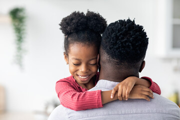 Closeup portrait of african american little girl hugging her dad
