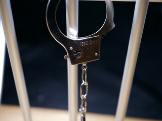 Handcuffs swing on prison bars close up shot