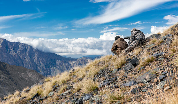 Couple of people in camouflage clothing are conducting covert surveillance in optical devices in the mountains.
