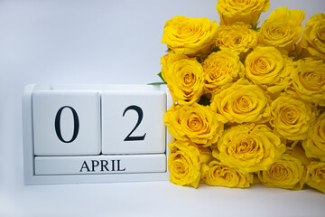 Wooden, white calendar April 2 and yellow roses on a white background. Holiday concept, plan, important event. High quality photo