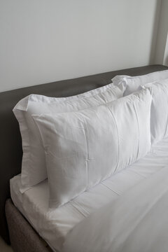 Close up shot of white pillows at head of the bed. Clean bed linen. Clean made-up bed. Comfort and rest concept.