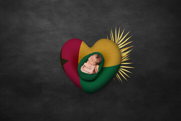 Newborn portrait on heart in color of national flag. Photography peace concept. Guinea-Bissau
