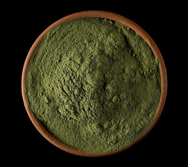 Organic powder wheat grass, pile in clay pot isolated on black, top view
