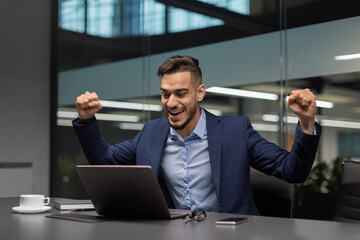 Emotional arabic businessman celebrating success at office