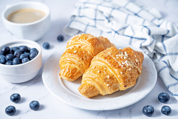 Fresh croissants with berries and cup of coffee