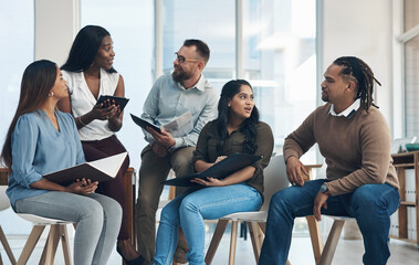 Fototapeta premium Our typical brainstorming session. Cropped shot of a diverse group of businesspeople sitting together and having a discussion in the office.