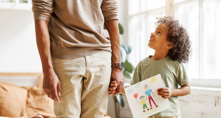 Cute little african american boy son holding hand drawing with happy family for dad on Fathers day