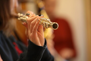 A musical instrument in the hand of a girl playing a flute with her fingers on the keys close-up.Music concept background image with selective focus