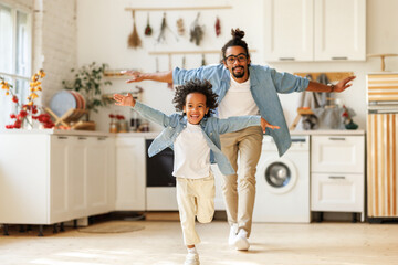 Happy funny african american family excited little boy son having fun with father at home