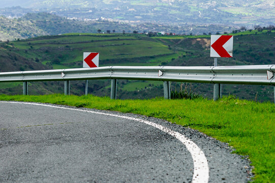 red and white warning signs before a dangerous road bend in a mountainous area