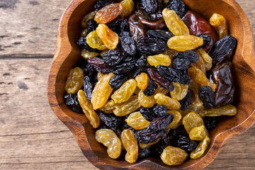 golden and black raisins on wooden table background.