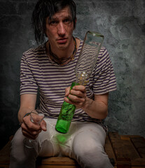 Dirty black hair man with alcohol glasses and bottles and old stone wall