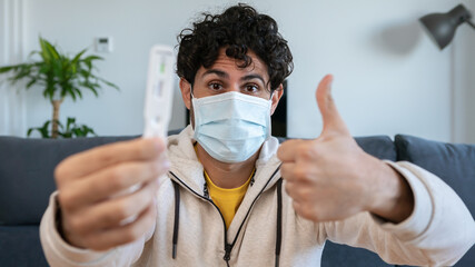 Happy caucasian person wearing mask and showing negative Covid-19 test at home