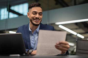 Happy middle eastern businessman reading marketing report
