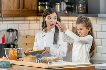Mother and little daughter baking together in a home kitchen making a pie. Mother and daughter bonding.