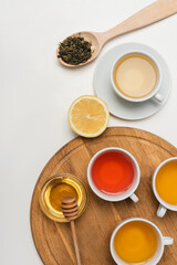 Obraz na płótnie Canvas Top view of cups of tea near honey and lemon on white background.