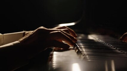 Male hands touch piano keys and play fast jazz melody. Pianist plays chords creating music on piano in dark. Keys of musical instrument. Musician's fingers close up. Slow motion ready at 59.94fps.