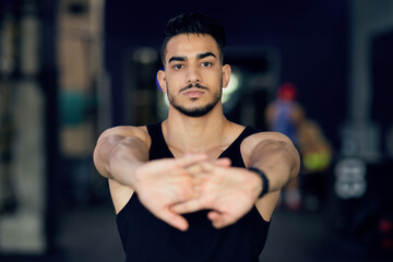 Fototapeta premium Portrait Of Sporty Young Arab Man Stretching Arms At Camera