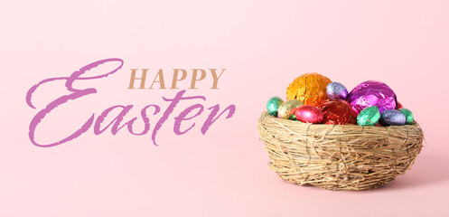 Nest with colorful chocolate eggs and text HAPPY EASTER on pink background
