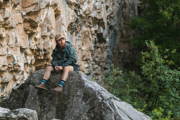 Fashionable outdoorsy man sitting on a rock