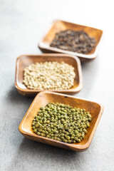 Three different types of pepper spice. Green, white and black peppercorn in bowls.
