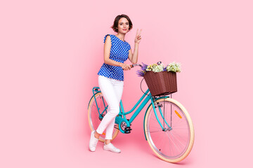 Full length photo of cool millennial brunette lady drive bicycle show v-sign wear blouse pants...