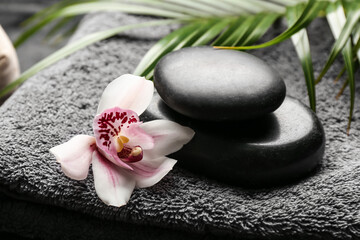 Spa stones with orchid flower on bathing towel, closeup