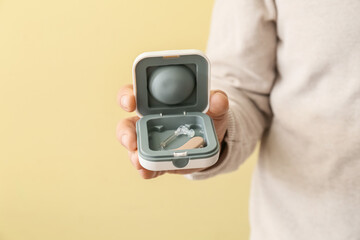 Doctor with hearing aid on color background, closeup