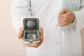 Doctor with hearing aid on light background, closeup
