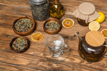 Cup near tea, honey and bowls on wooden surface.