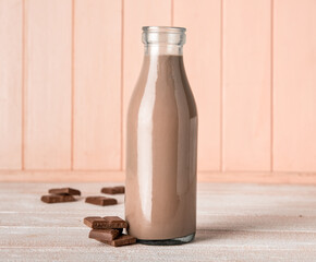 Bottle of delicious chocolate milk on wooden background