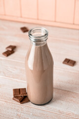 Bottle of delicious chocolate milk on wooden background