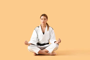 Fotobehang Female karate instructor meditating on color background © Pixel-Shot