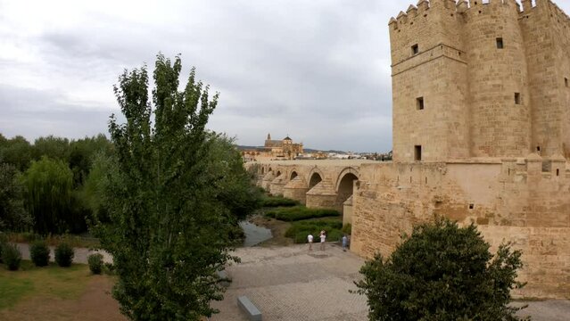 Cordoba, Spain, September 13, 2021: SLOW MOTION The defensive tower from the Muslim era: the Calahorra Tower, Guadalquivir River, and the Roman Bridge, with Cordoba Mosque-Cathedral in the background.