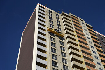 Detail of large concrete residential building with flats and apartments in construction with suspended access platform