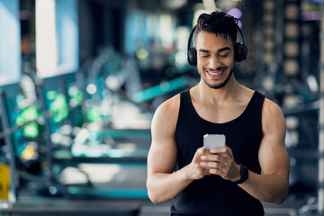Happy Young Arab Man Messaging On Smartphone While Relaxing After Sport Workout