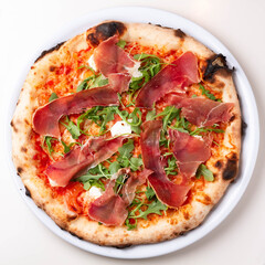 delicious italian pizza with tomatoes, ham, salami, cheese on a white background