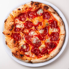 delicious italian pizza with tomatoes, ham, salami, cheese on a white background
