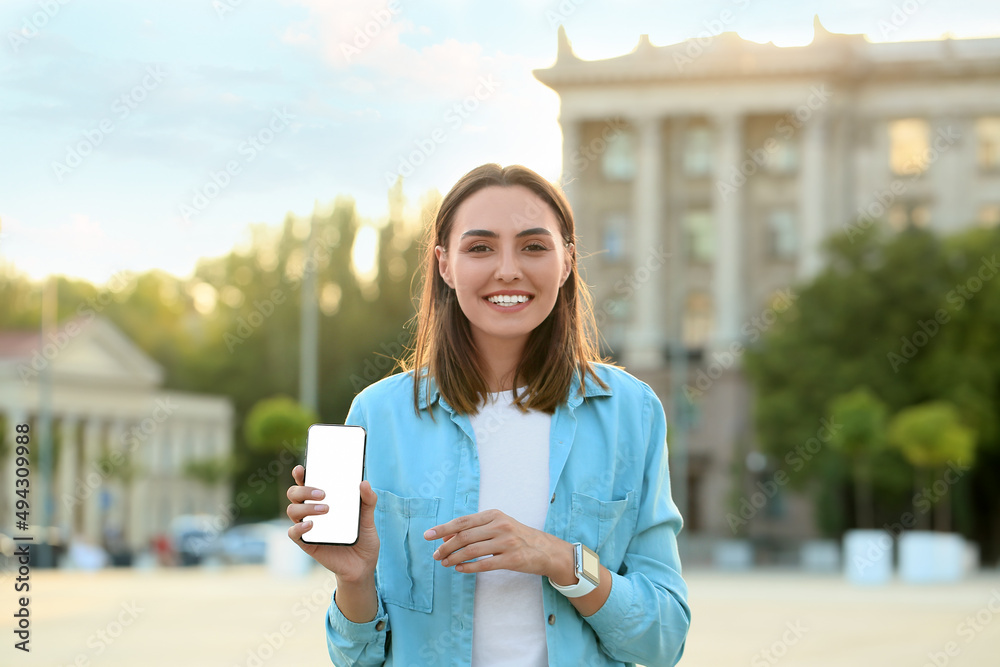 Wall mural Young female tourist with phone outdoors