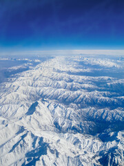 Fototapeta premium Landscape of the Alps. View from the window of the plane on the snowy mountains. Top view.