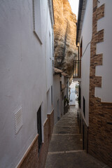 Narrow street with houses caves built into the mountain in the beautiful and famous white village of Setenil de las Bodegas at daylight, Cadiz province, Andalusia, Spain