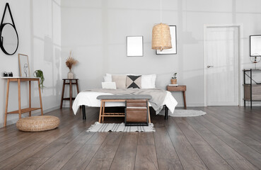 Stylish bench near comfy bed in light bedroom