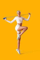 Sporty young woman with skipping rope on color background