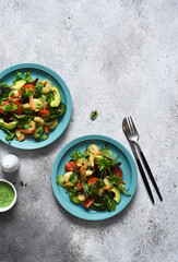 Green mix salad with tomatoes and shrimp and sauce on a concrete background. View from above