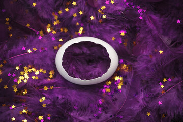 White egg shell in purple feathers with golden stars close-up
