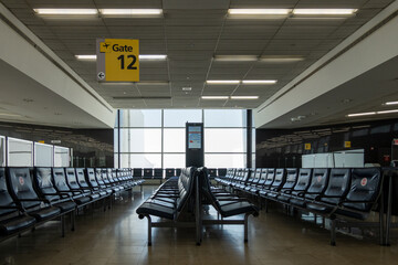 Empty seats in waiting area at Gate 12 - 494312569