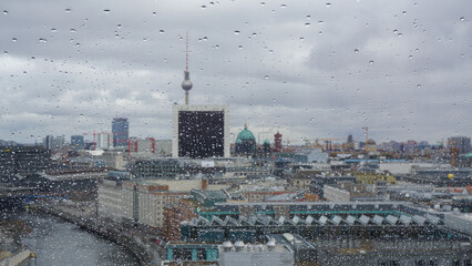 Obraz premium View on Berlin and tv tower on a rainy day. Shot taken from Bundestag building, raindrops on the window